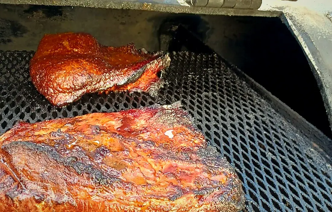 Bark-crusted brisket resting on the smoker grate