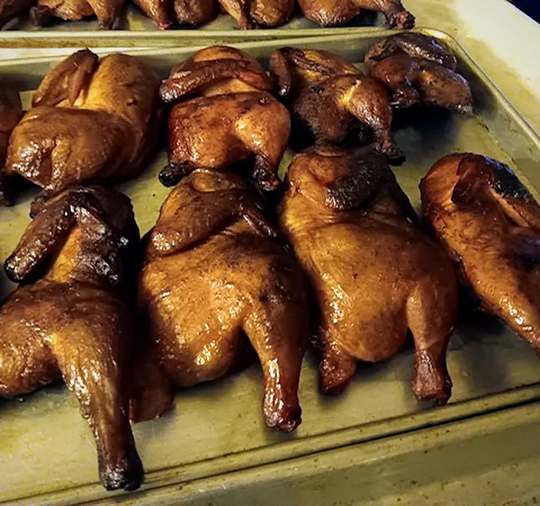 Pans of smoked chicken halves lined up for an order